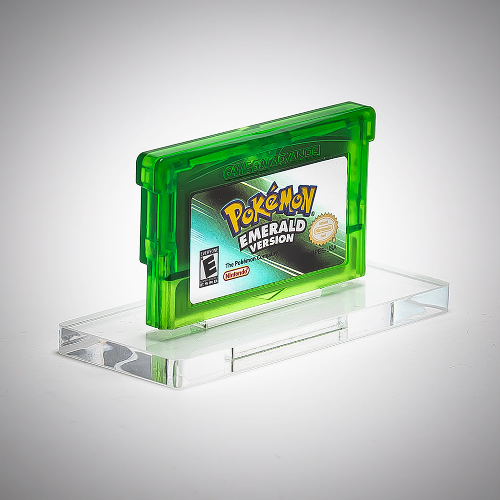 Pokémon Emerald Version game cartridge on a clear stand with a gray background