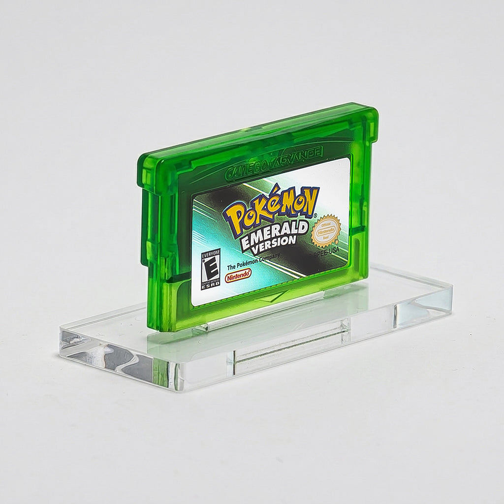 Pokémon Emerald Version game cartridge on a clear stand with a gray background