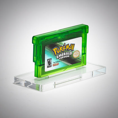 Pokémon Emerald Version game cartridge on a clear stand with a gray background